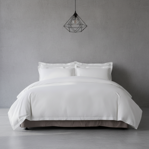 A luxury white hotel king bed with stacked white shams and a tailored taupe grey bed skirt against a textured grey wall.