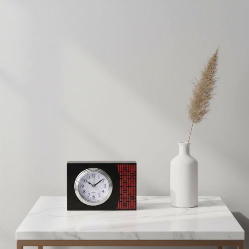 A premium black leather rectangular desk clock with an orange textured accent on a white marble tabletop next to a vase.