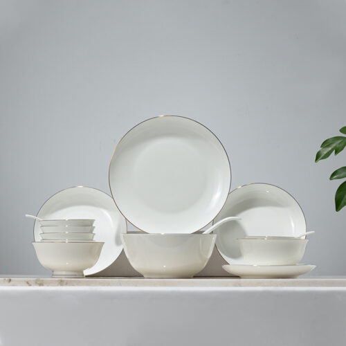 Galaxy luxury fine bone china dinnerware set with gold rim detailing featuring plates, bowls, and soup spoons on a marble display.
