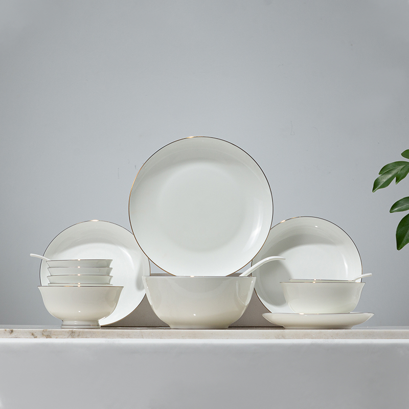 Galaxy luxury fine bone china dinnerware set with gold rim detailing featuring plates, bowls, and soup spoons on a marble display.