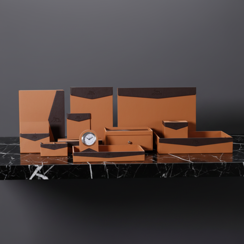 A comprehensive collection of tan and dark brown faux leather hotel desk accessories arranged neatly on a black marble countertop.