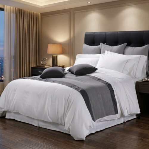 A luxury hotel king bed dressed in crisp white linens, featuring a charcoal grey bed runner and coordinating dark grey accent pillows against a tufted black headboard.