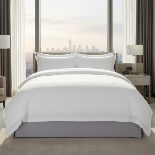 A luxury hotel king bed dressed in crisp white satin linens with a gold embroidered border duvet cover against a high-rise city skyline window view.