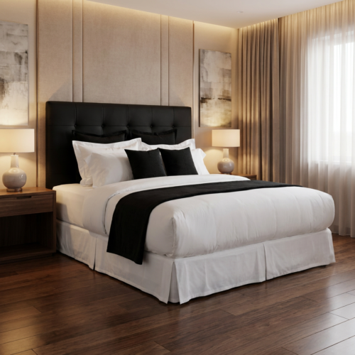 Luxury white hotel king bedding set with black velvet bed runner and black accent cushions styled on a king bed with black tufted leather headboard, white bed skirt, and warm beige panel wall in an upscale hotel room