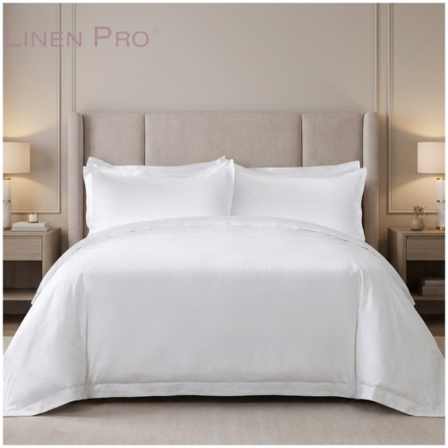 A luxury contemporary hotel king bed dressed in an immaculate white sateen bedding set with wide-flange Oxford pillowcases against a plush beige wingback headboard.