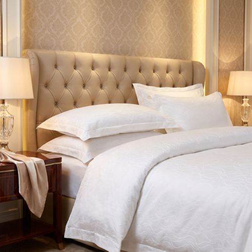 ELIYA premium white wave jacquard hotel sheets and layered Oxford pillow shams styled against a tufted beige leather headboard.