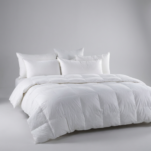 A luxury hospitality king bed styled with a thick white box-stitch goose down duvet insert and a layered arrangement of five plush pillows.