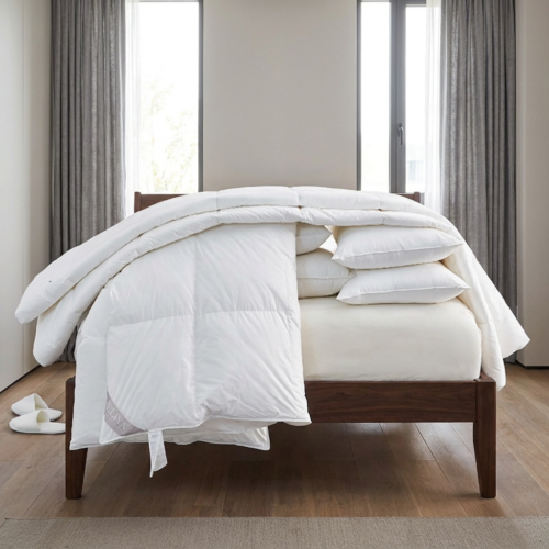 Eliya luxury white goose down duvet insert draped artistically over a wooden hotel bed frame revealing plush stacked pillows and mattress topper.
