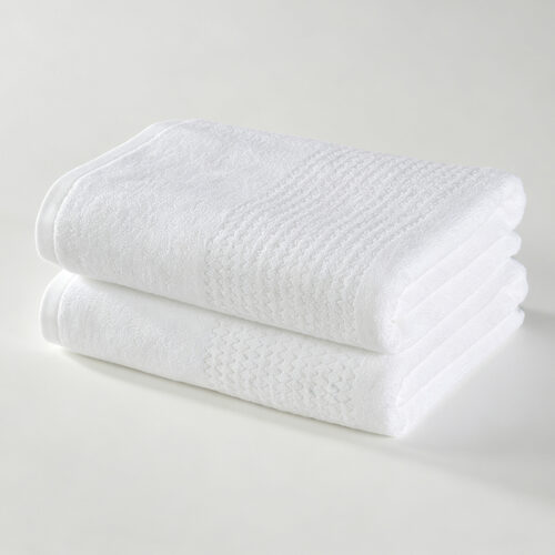 Stack of two folded white 100% cotton hotel towels with a subtle wave jacquard woven border.