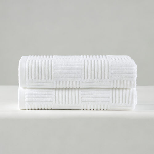 Stack of two folded white 100% cotton hotel bath towels featuring a raised checkered grid texture.