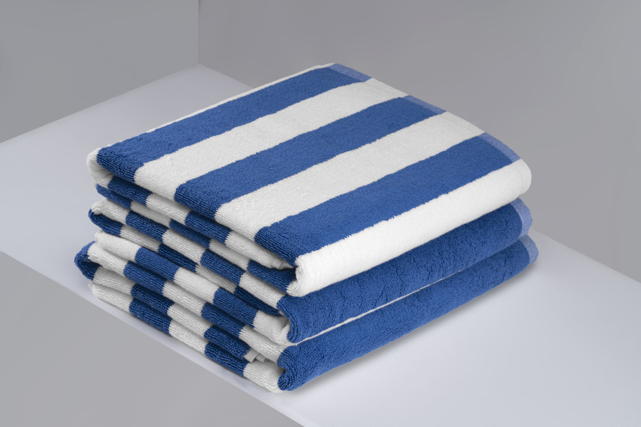 Stack of bright blue and white striped hotel pool towels.