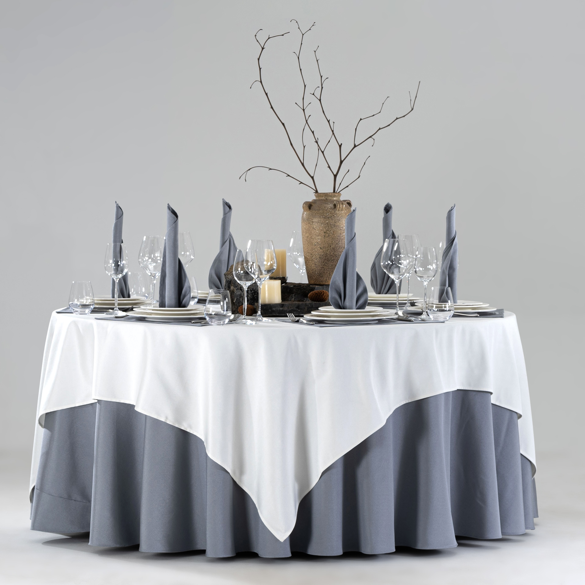 Product collage of a hotel round banquet table styled with white square overlay, slate blue skirt, embroidered placemats, and blue floral centerpiece.