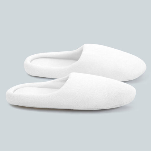 Pair of plain white plush velour closed-toe hotel slippers with soft padded borders.